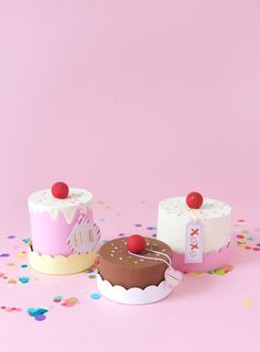 two small cakes sitting next to each other on a pink surface with confetti