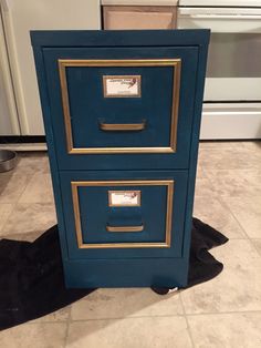 a blue file cabinet with gold trim on the front and bottom, sitting in a kitchen