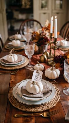 a table set for thanksgiving dinner with white pumpkins