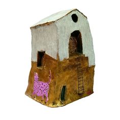 a small clay house with a cow painted on it's side and a ladder leading up to the roof