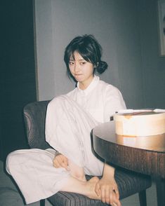 a woman sitting in a chair with her foot on the table and looking at the camera