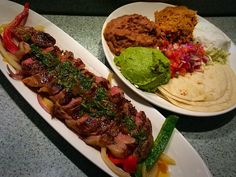 two white plates filled with different types of food on top of a counter next to each other