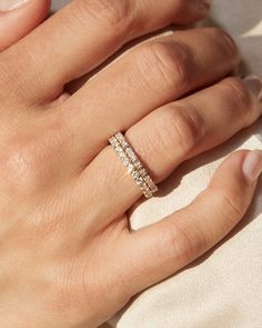 a woman's hand wearing a ring with three rows of diamonds on the band