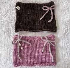 two knitted items are laying on the bed