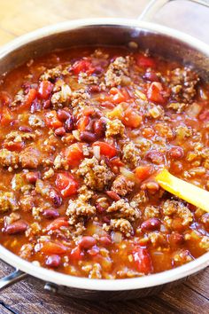 a pot filled with chili and meat on top of a wooden table