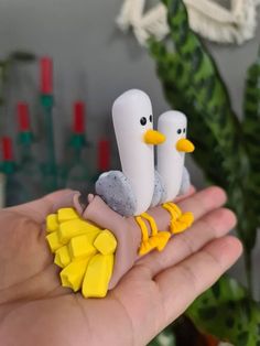 two birds sitting on top of each other in someone's hand with yellow and white decorations