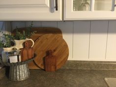 a wooden cutting board sitting on top of a counter next to a potted plant