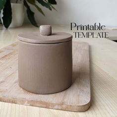 a ceramic container sitting on top of a wooden cutting board next to a potted plant