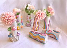 colorful vases with flowers and decorations on a white sheeted surface in front of a white backdrop