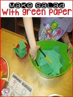 a child is cutting out green paper in a bowl with scissors on the table next to it