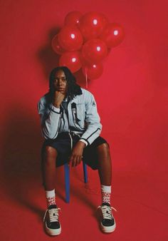 a person sitting on a chair with red balloons