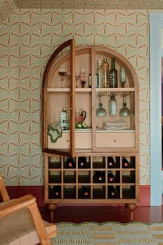 a wooden cabinet filled with lots of bottles next to a wall mounted wine glass rack