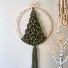 a crocheted christmas tree hanging on the wall next to a white birch tree