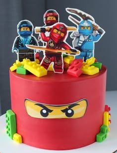 a red cake with lego figures on top of it and decorations around the edges that look like ninjas