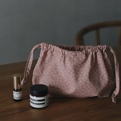 two small containers sitting on top of a wooden table next to a pink bag with white dots