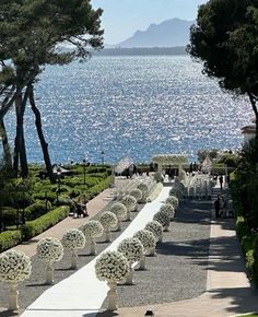 an outdoor wedding setup with white flowers and greenery on the walkway by the water