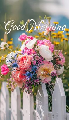 a bouquet of flowers sitting on top of a white fence with the words good morning