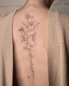 a woman's back with a flower tattoo on her left shoulder and the upper part of her body