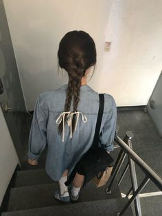 a girl with long braids is walking up the stairs