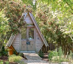 a small wooden building with a door and windows in the middle of some trees,