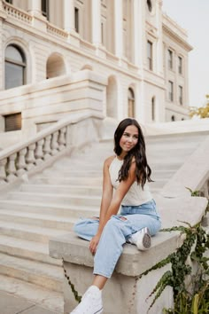 a woman sitting on the steps in front of a building