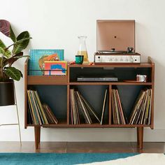 a record player sitting on top of a wooden shelf next to a potted plant