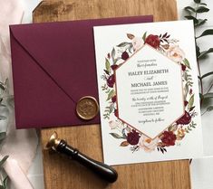 the wedding stationery is laid out on top of a wooden table next to a wax seal