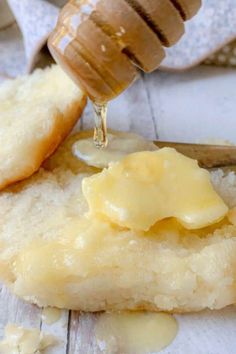 a piece of bread with butter on it next to a honey dipper