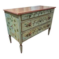 an old dresser painted with flowers and leaves on it's sides, against a white background