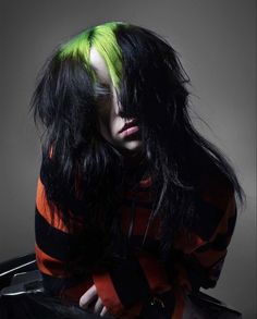 a woman with green hair sitting on top of a suitcase