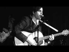 a man holding a guitar and singing into a microphone