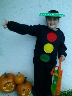 a young boy wearing a costume made to look like a traffic light and holding two pumpkins