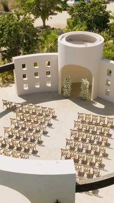 an aerial view of chairs and tables in front of a white building with trees on the other side