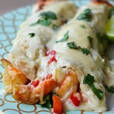 a close up of a plate of food with shrimp and cheese covered in sauce, garnished with cilantro