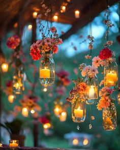 mason jars filled with flowers and lit candles are hanging from a wooden structure over a table