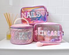 The ultimate high-shine glam bag - perfect for your minis GRWM routine! Our pink "MAKEUP" metallic quilted glam bag is a definite need for the girl who loves to glam. Featuring pastel glitter varsity letter applique patches and a pearl handle to give a little extra special touch! Measures Approx. - 5.50”H x 8.00”W x 5.00”DManufacturer Style No. - MKUP-RTC72 Varsity Letter, Glam Bag, Train Case, Types Of Buttons, Pink Makeup, Appliqué Patch, Large Backpack, Parisian Chic, The Girl Who