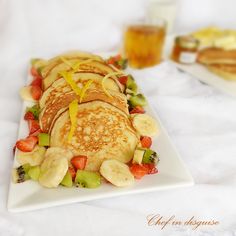 pancakes with fruit and syrup on a white plate