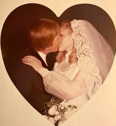 a bride and groom kissing in front of a heart shaped photo with flowers on it