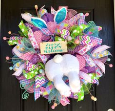 a wreath with a white stuffed animal on it's front door and happy easter message