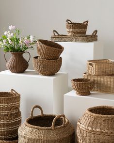 wicker baskets and vases are stacked on top of each other with flowers in the background