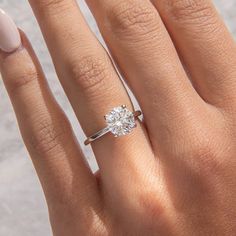 a woman's hand with a diamond ring on her finger and the other hand holding an engagement ring