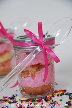 two small jars filled with pink frosting and sprinkles