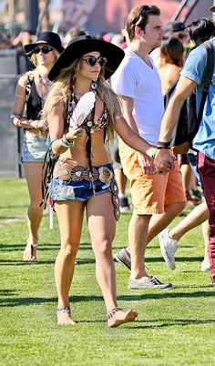 two people walking in the grass with hats on their heads and one person holding hands