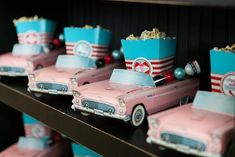 pink and blue cars with popcorn buckets on the hood are sitting on a shelf