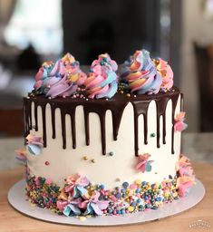 a white cake with chocolate icing and sprinkles on the top is sitting on a table