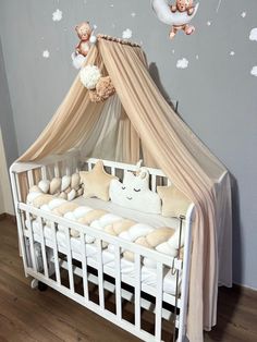 a baby crib with two teddy bears hanging from it's canopy and stuffed animals on the bed