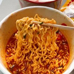 a bowl of ramen with chopsticks in it and another bowl full of noodles