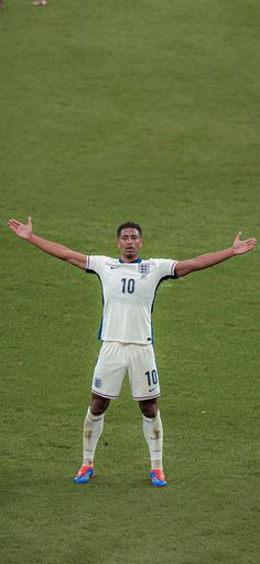 a man standing on top of a soccer field holding his arms out to the side