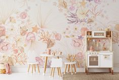 a room with floral wallpaper and white chairs in front of a small wooden table