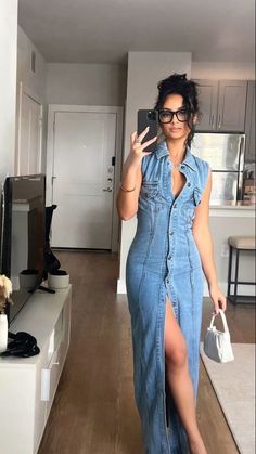 a woman taking a selfie in her living room wearing a denim dress and high heels